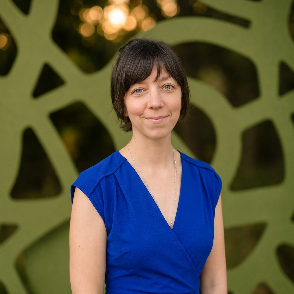 Katie Pendergast, Director of Systems and Experience, smiling in a blue dress